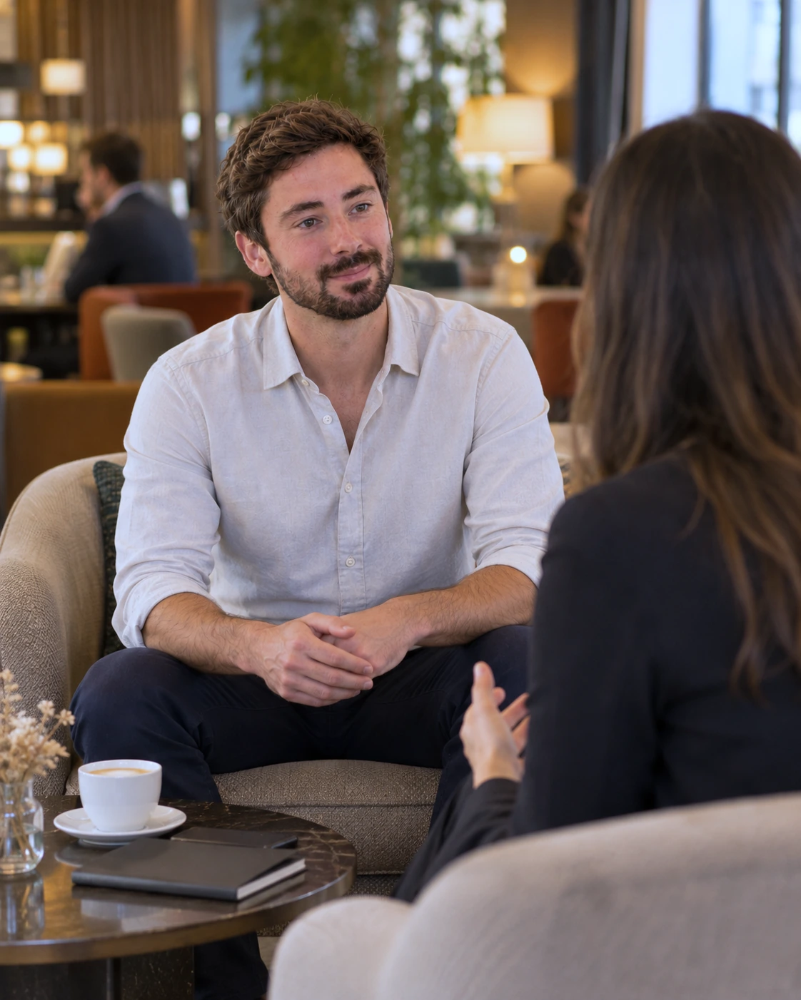 Sébastien Lucu à l'écoute d'une cliente pendant une séance de coaching, dans un salon calme autour d'un café